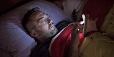 Un hombre lee a oscuras con su smartphone en la cama. GETTY IMAGES